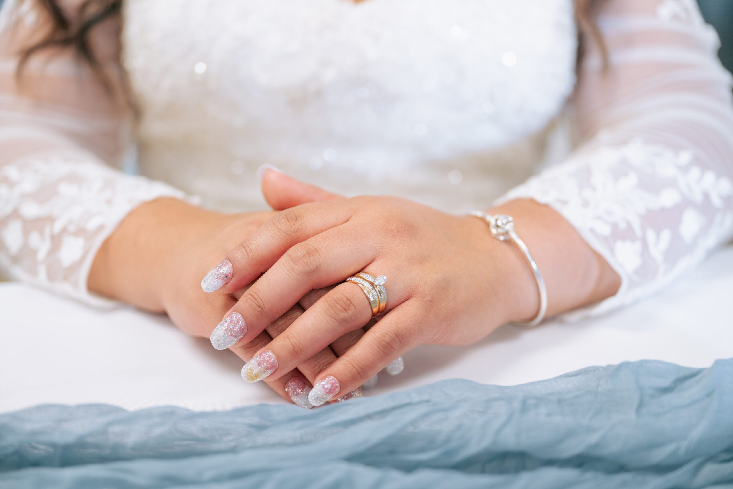 Close-up to the hands of a bride's ring with white dress.